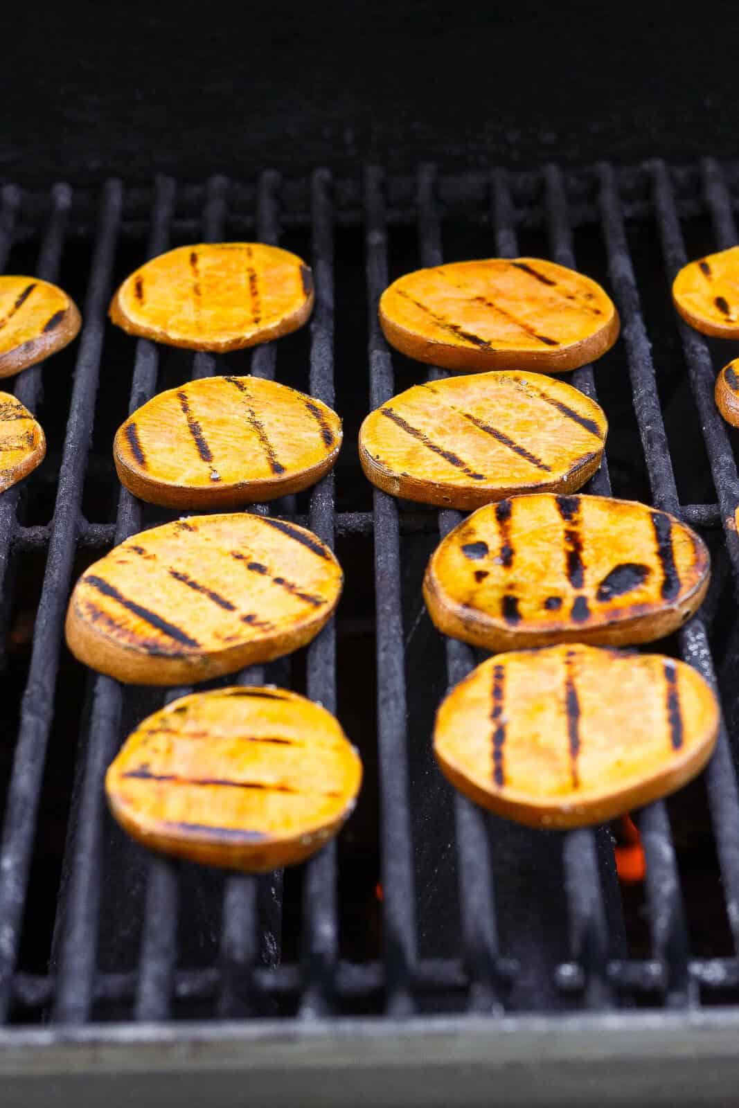 Sweet potatoes on the grill with grill marks.