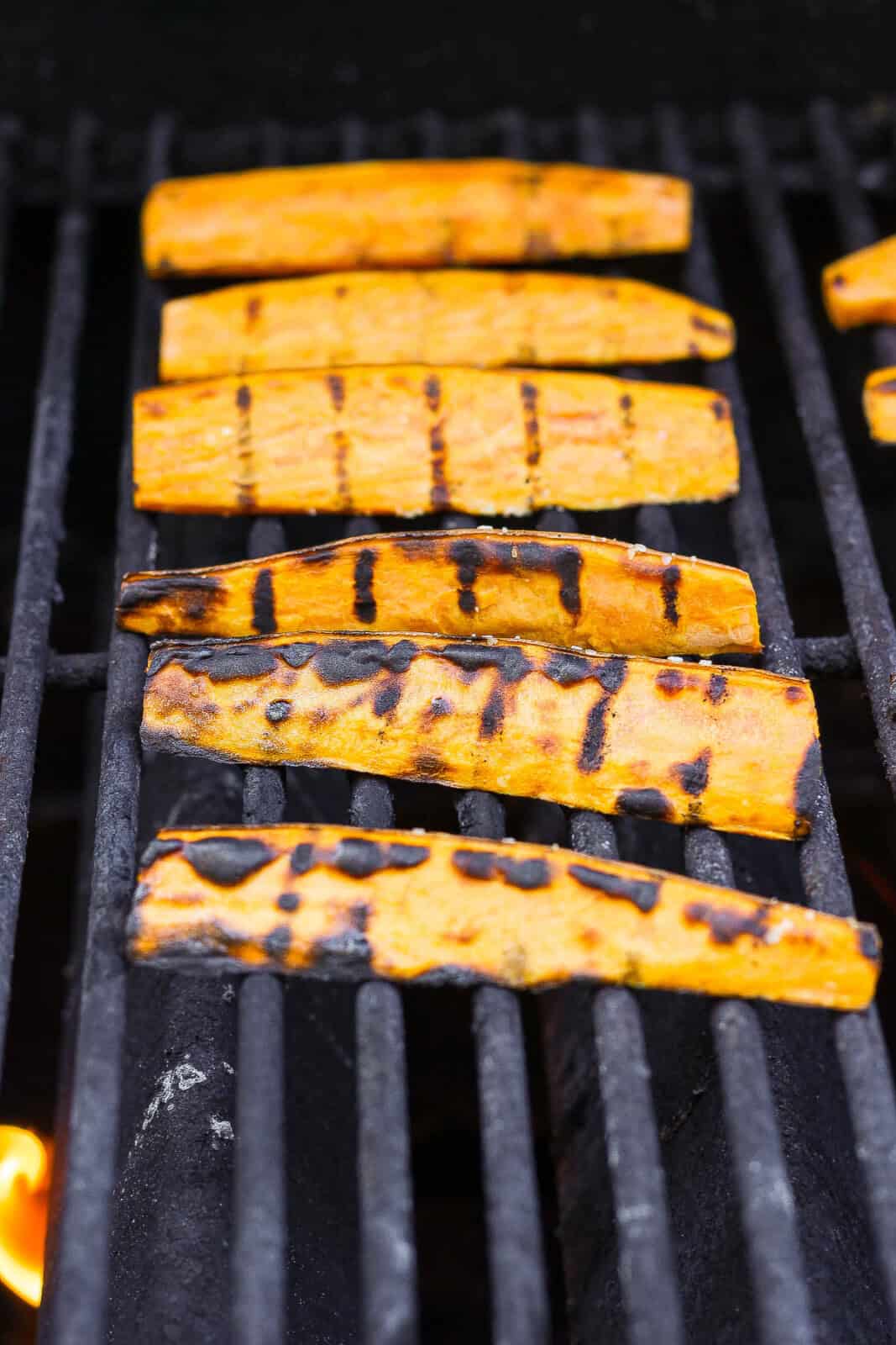 Sweet potato wedges on the grill with grill marks.