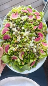 Someone holding a fully assembled spring salad on a serving platter.