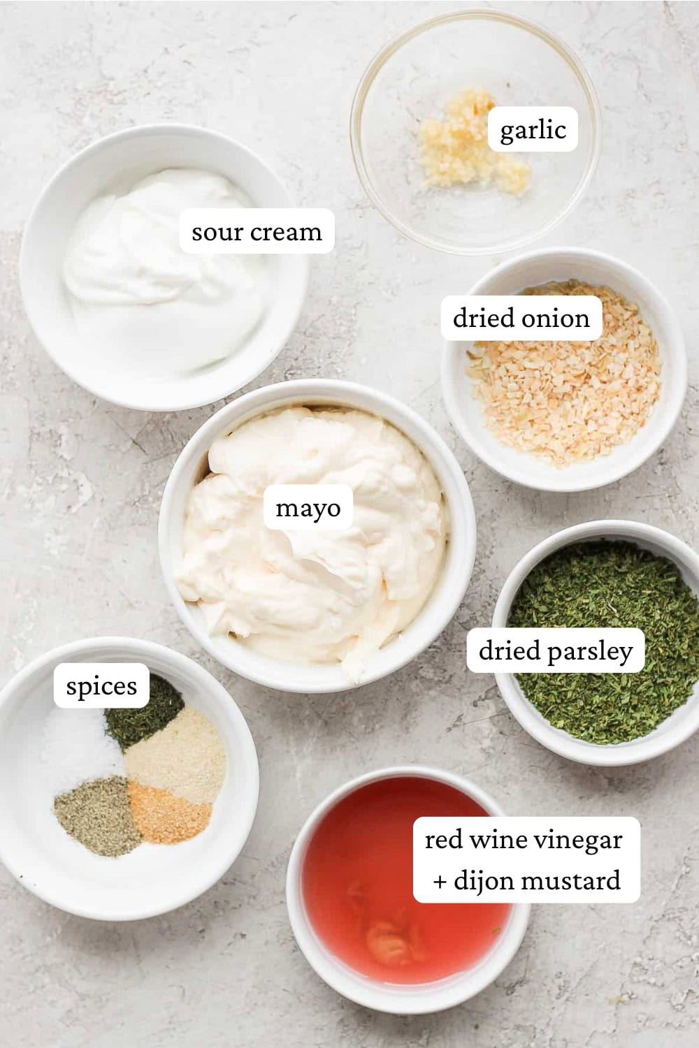 Ingredients for a homemade veggie dip in bowls with labels.