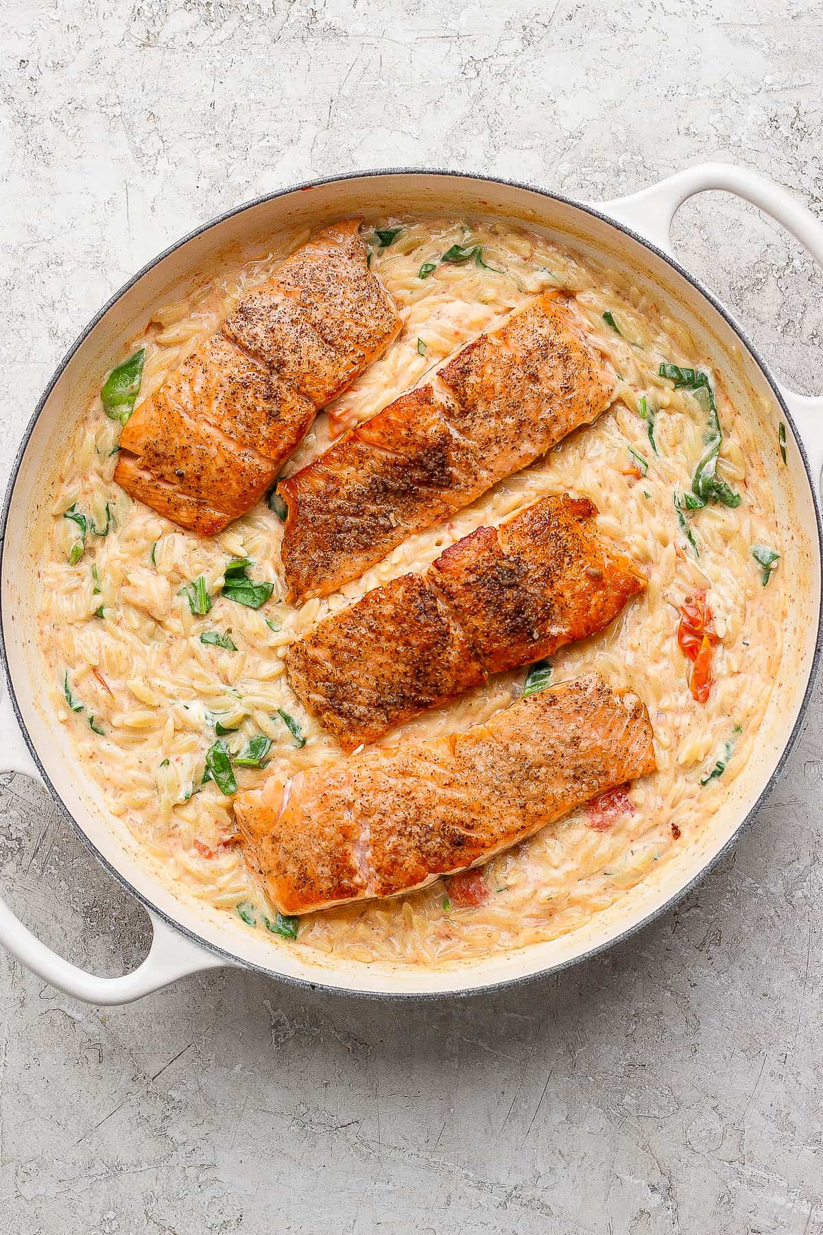 Fully cooked salmon orzo in a large braiser.