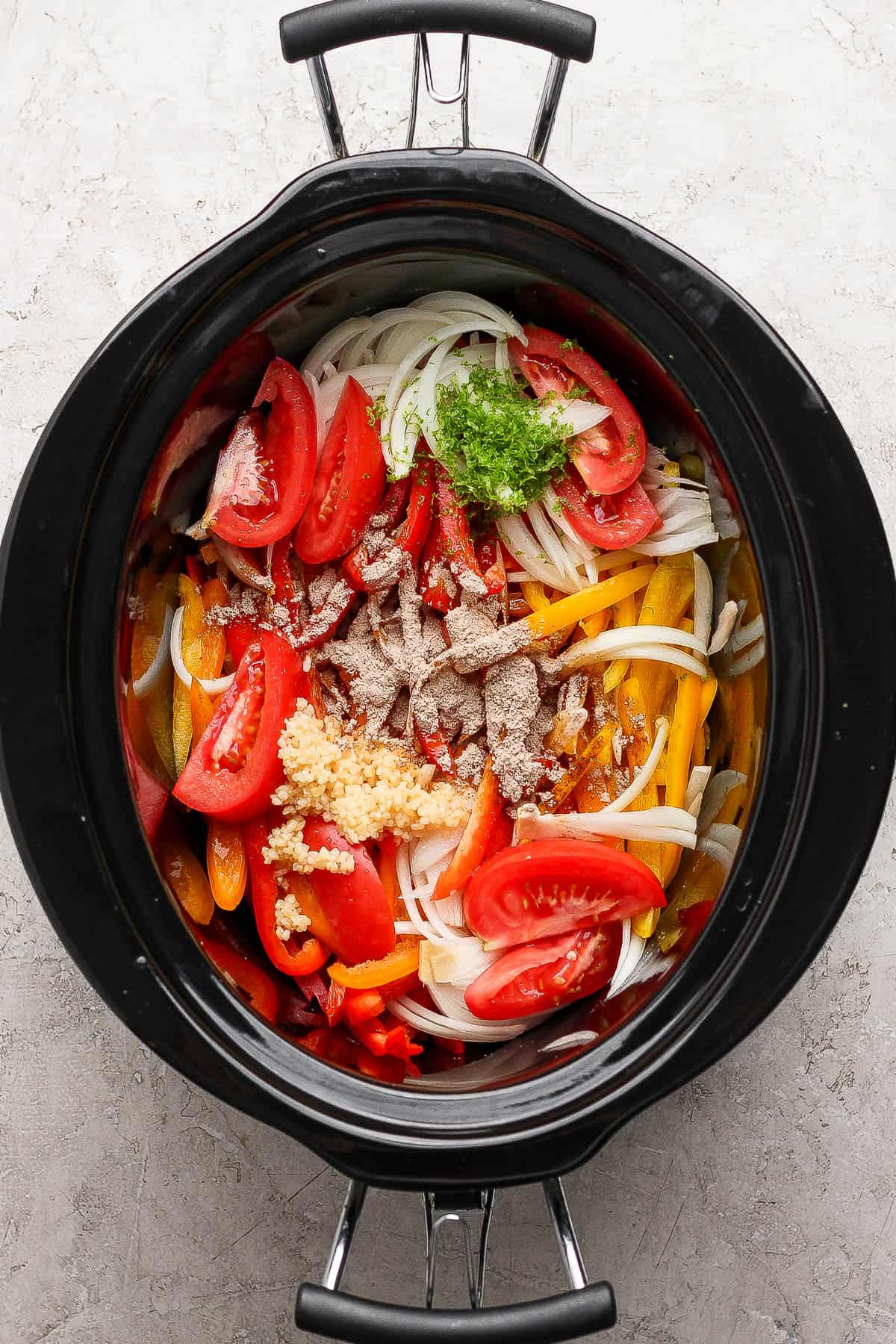 Peppers, onion, tomato, lime zest, lime juice, garlic, and half the fajita seasoning the the slow cooker for slow cooker chicken fajitas.