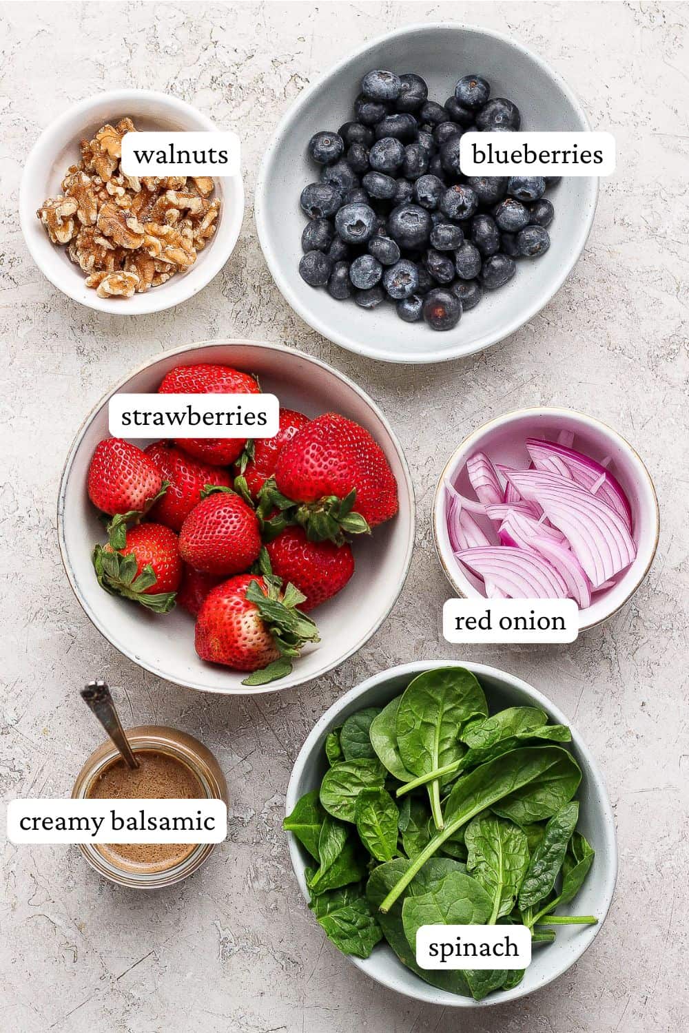 Ingredients for Strawberry Blueberry Spinach Salad separated into small bowls.