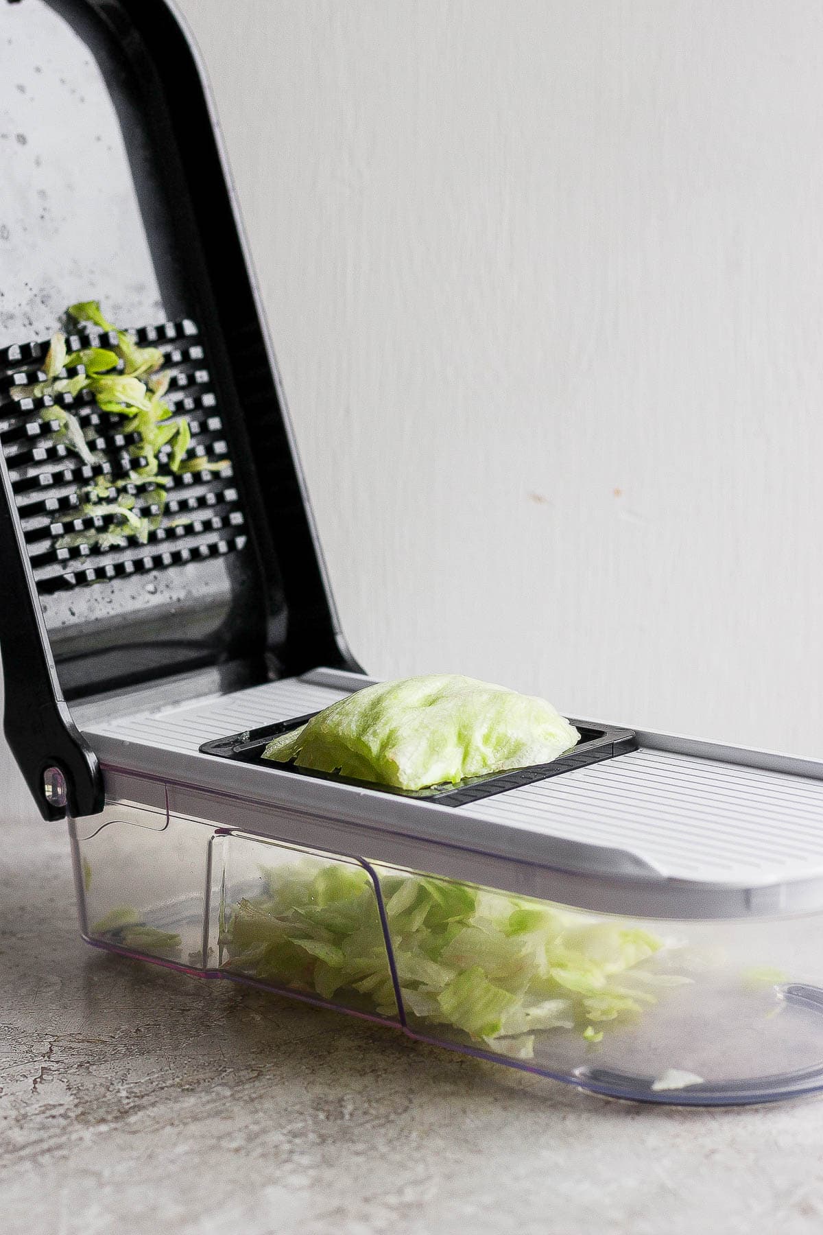 Iceberg lettuce being cut in a vegetable chopper to make a Sub in a Tub.