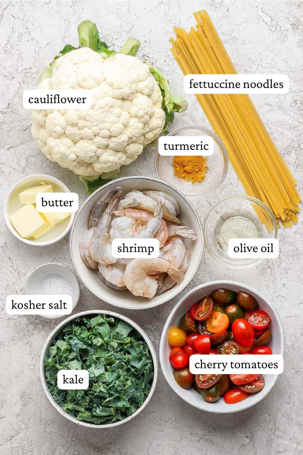 Ingredients for turmeric pasta with shrimp and cauliflower in separate bowls with labels.