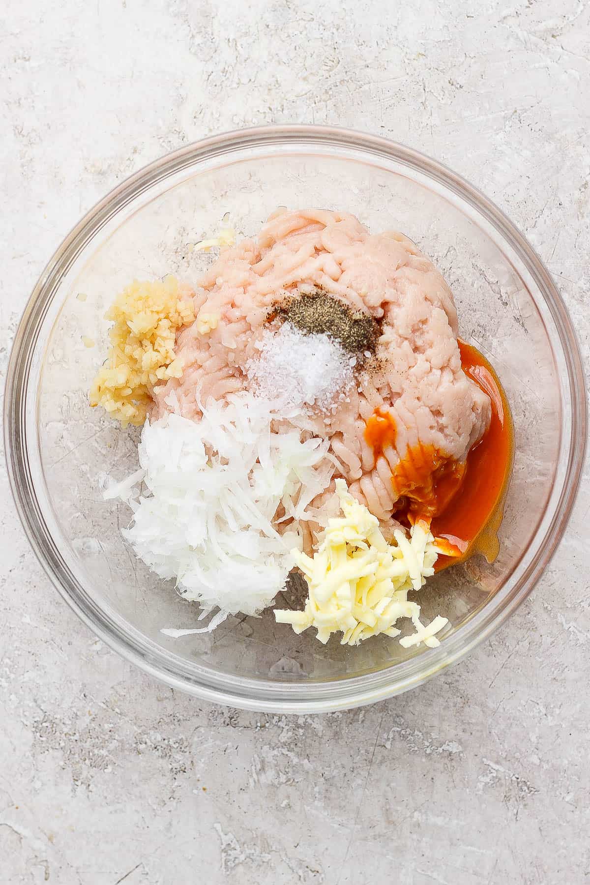 Ingredients for a buffalo chicken smash taco patty in a glass bowl before mixing.