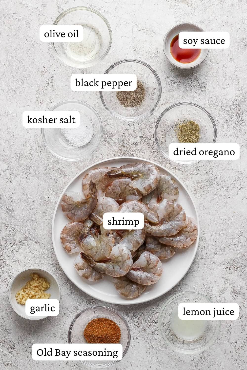 Ingredients for grilled shrimp skewers in bowls with labels.