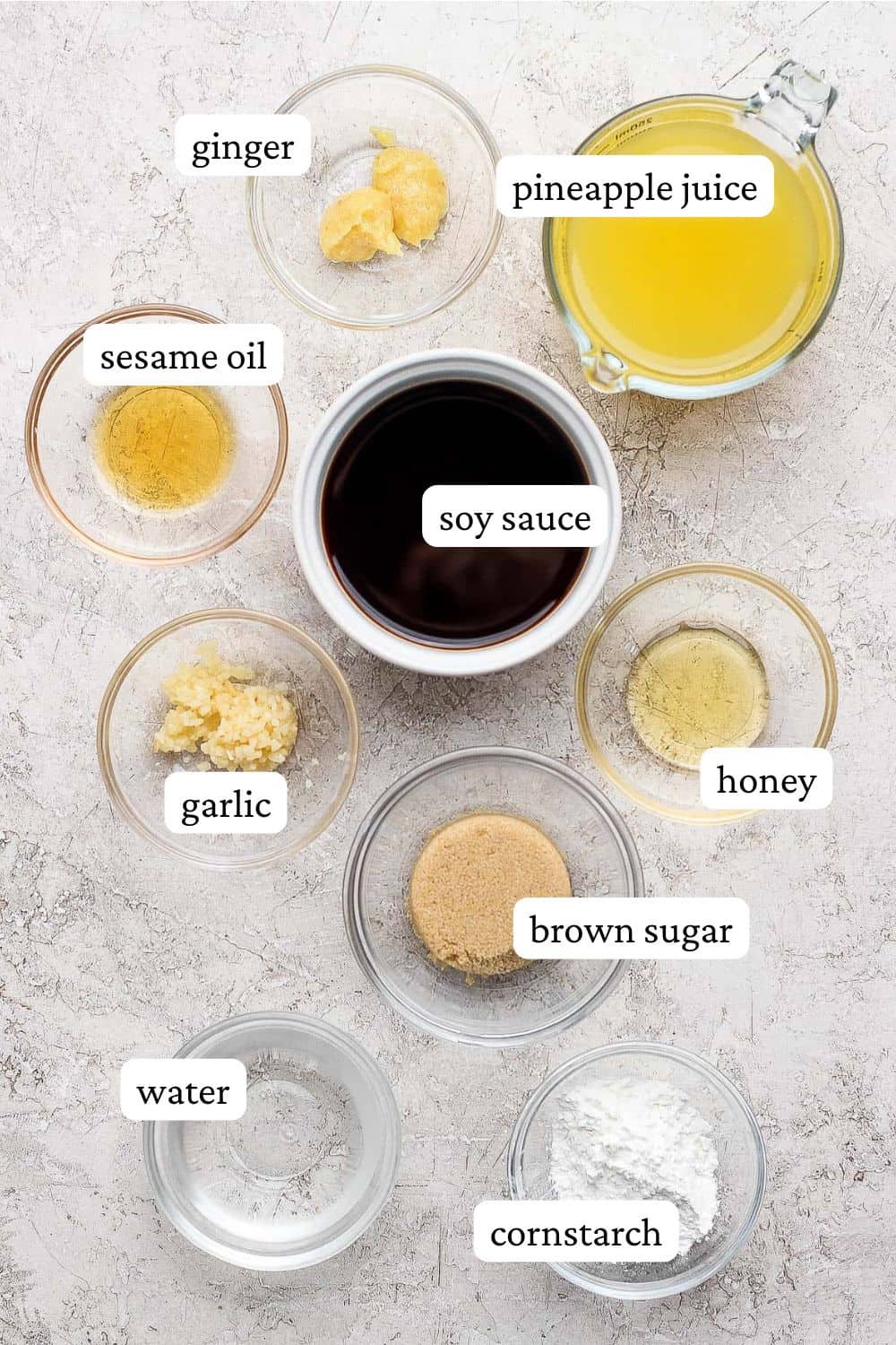 Pineapple Teriyaki sauce ingredients in individual bowls; ginger, pineapple juice, sesame oil, soy sauce, honey, garlic, brown sugar, water, cornstarch.