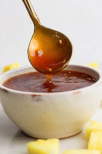 Pineapple teriyaki sauce in a bowl with a spoon scooping some out.