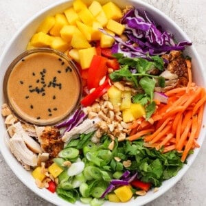 A fully assembled Thai peanut rotisserie chicken salad with a small dish of the dressing.