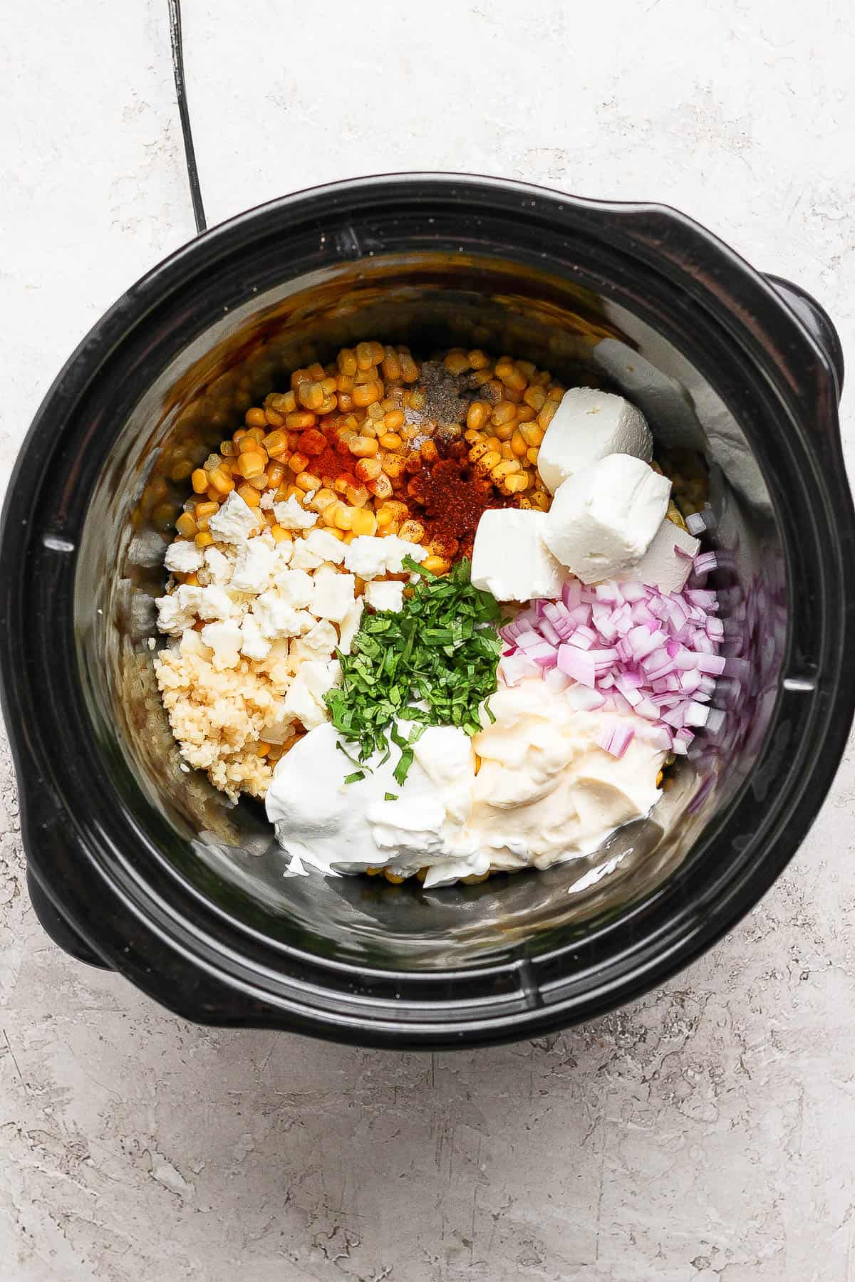 The street corn dip mixture in a crockpot before being mixed.