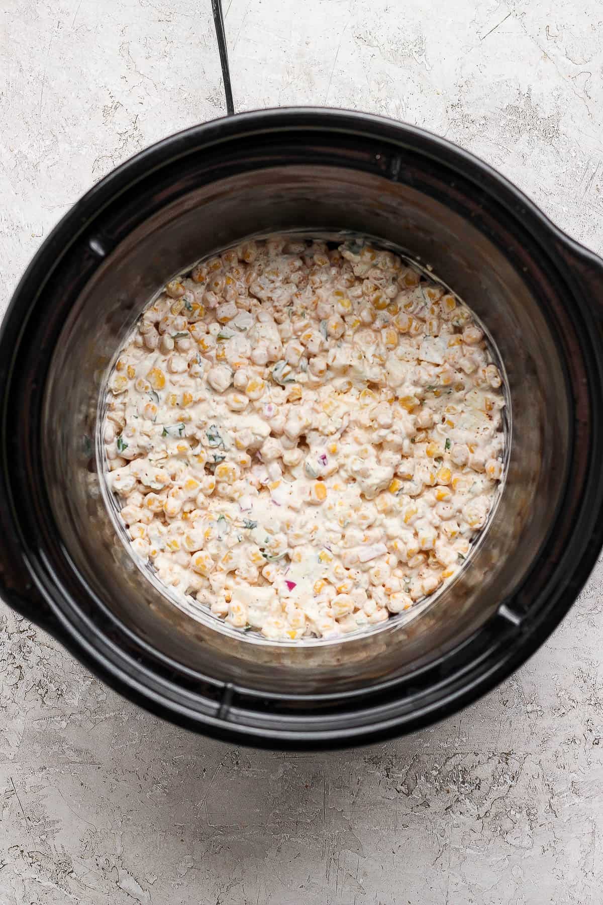 Fully mixed street corn dip in a crock pot before heating.