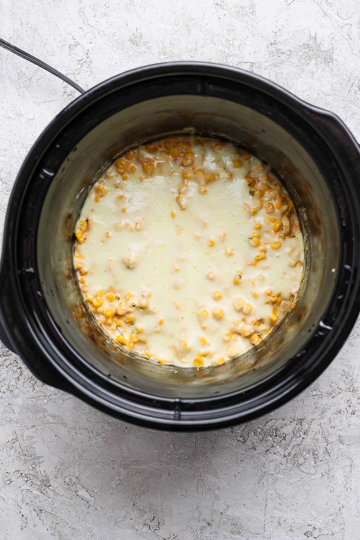Street corn dip in a crock pot with melted mozzarella cheese on top.