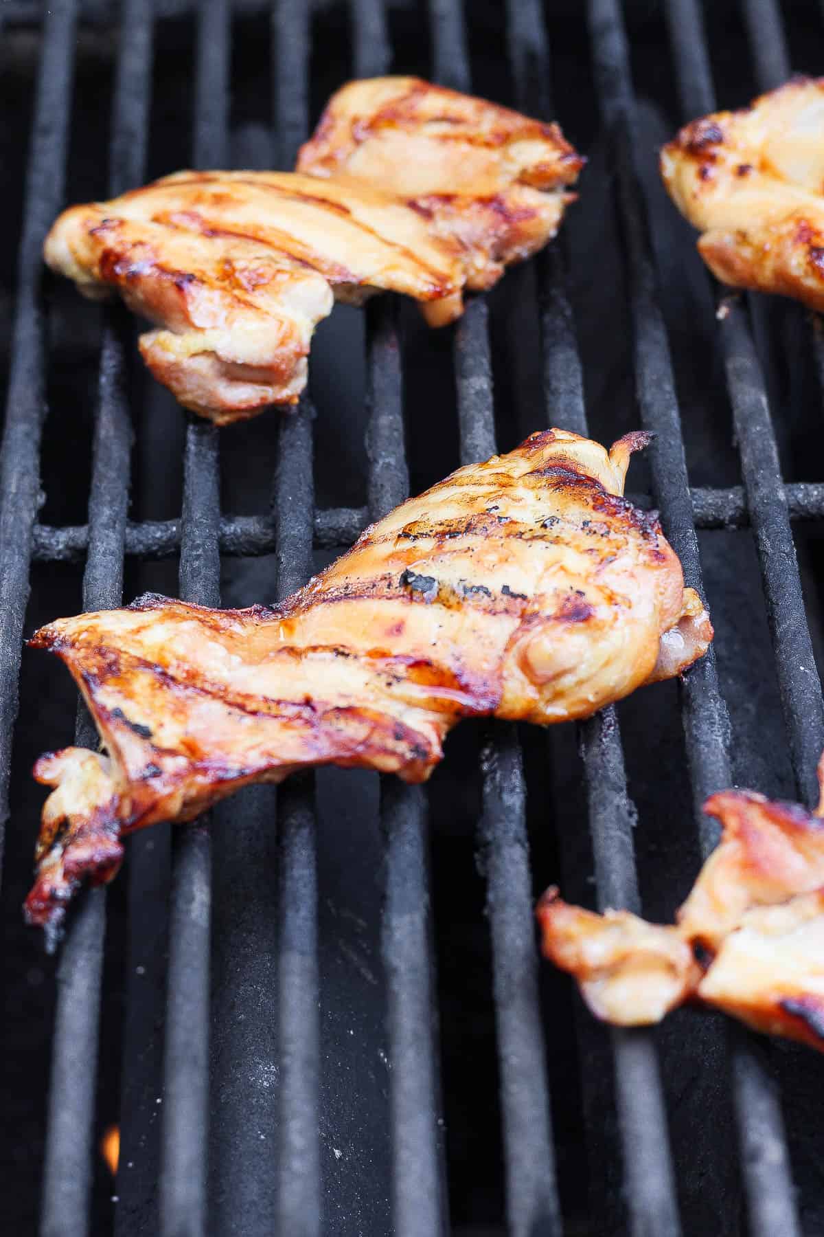 Grilled chicken thighs on a grill grate to make bang bang chicken salad.