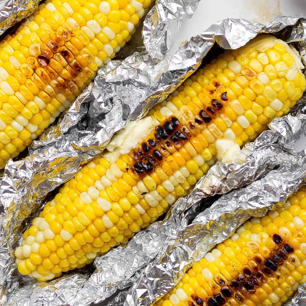 Three ears of Blackstone corn on the cob in aluminum foil.
