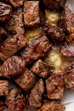 Several Blackstone steak bites in a bowl lined with parchment paper and melted cowboy butter.