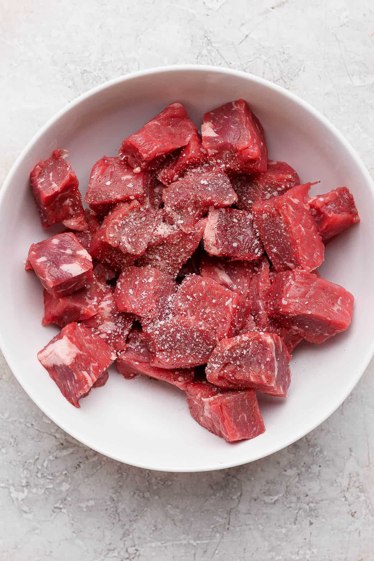 Blackstone steak bites in a bowl with salt and pepper before cooking.