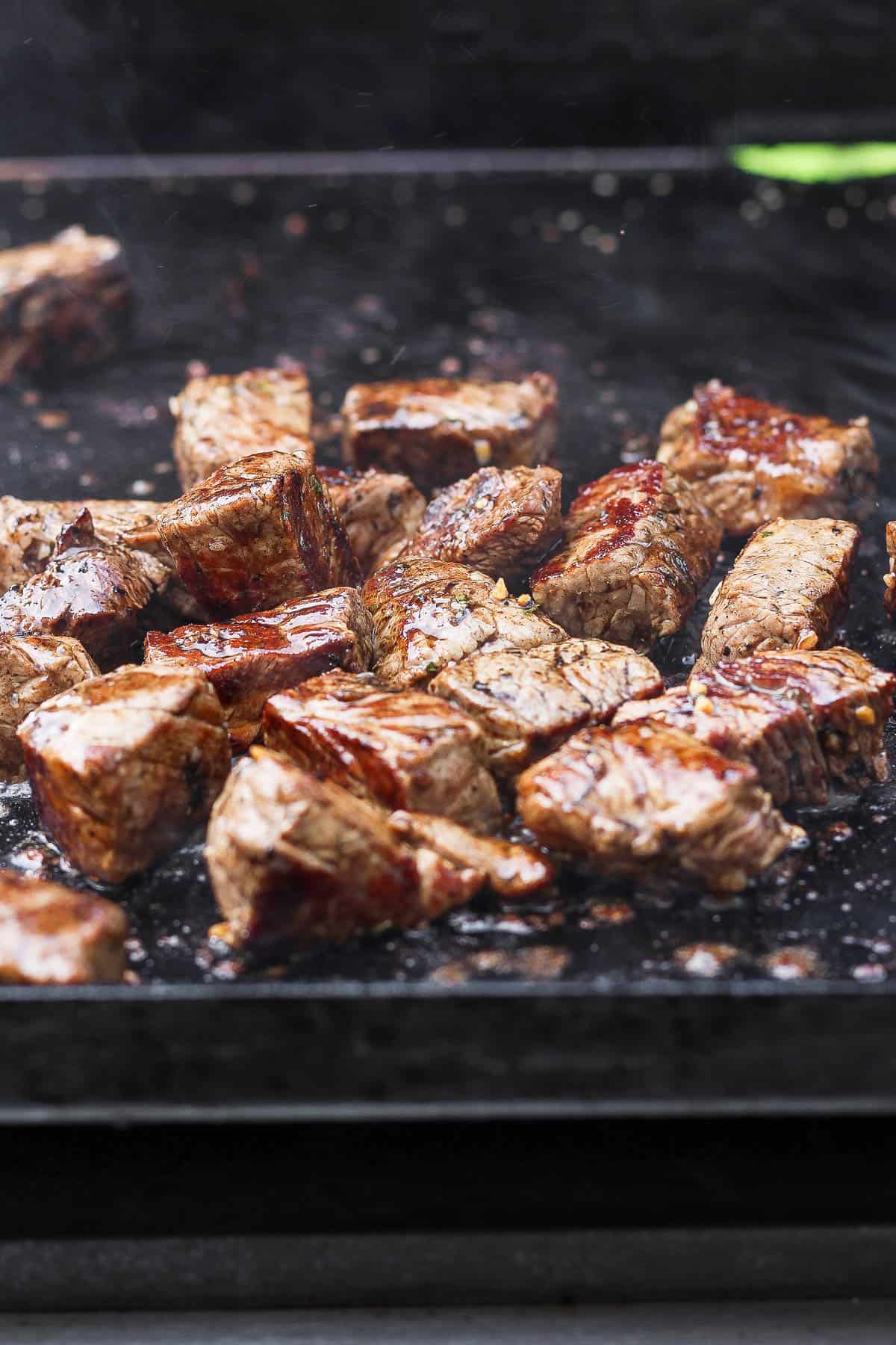 Blackstone steak bites cooking on a Blackstone griddle.