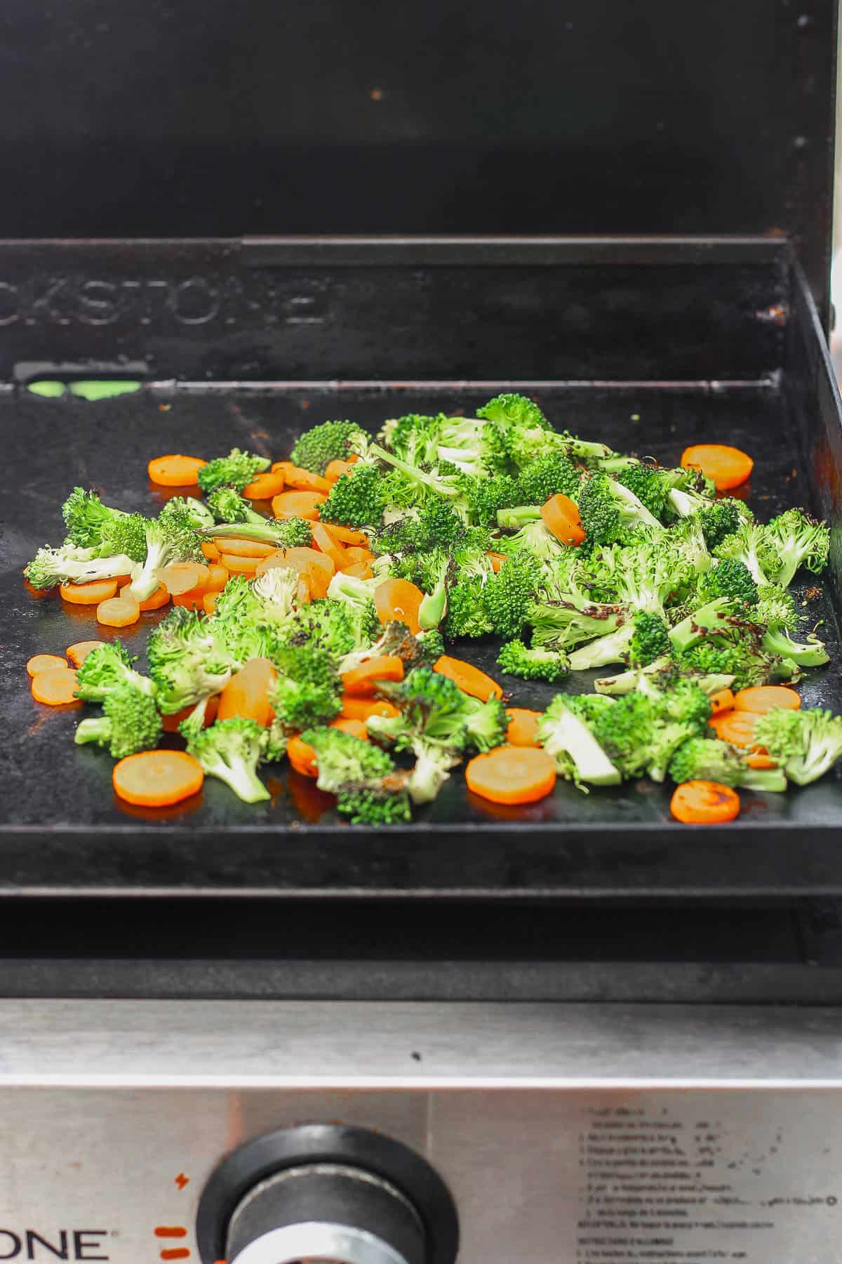 Broccoli and carrots cooking on a Blackstone to make Blackstone teriyaki chicken.