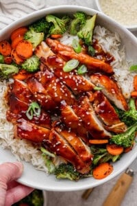 Someone holding a bowl of Blackstone teriyaki chicken over rice.