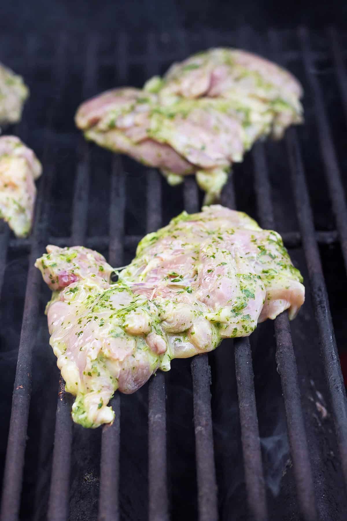 Cilantro lime chicken thighs placed on the grill before being flipped.