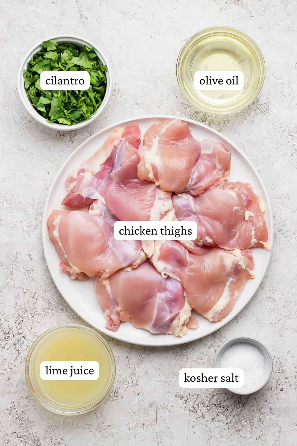 Ingredients for cilantro lime chicken thighs on a plate and small bowls with labels.