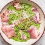 Cilantro lime marinade over several boneless skinless chicken thighs in a large bowl.