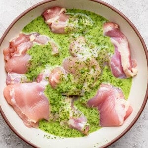 Cilantro lime marinade over several boneless skinless chicken thighs in a large bowl.