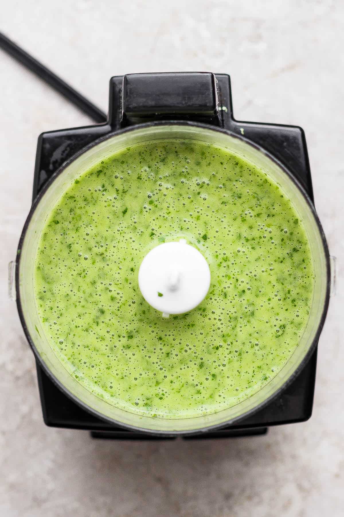 Cilantro lime marinade in a food processor after being blended.