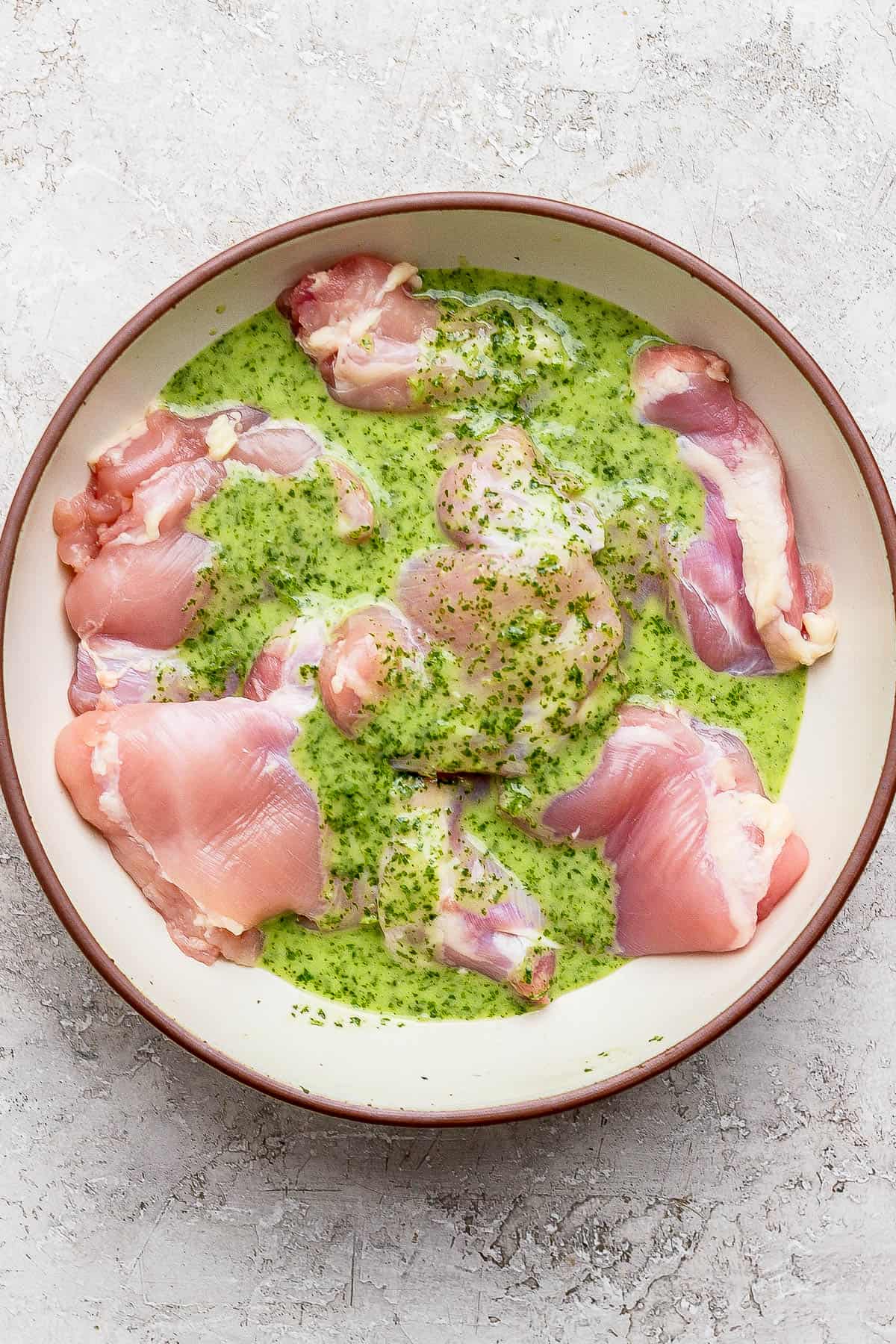 Cilantro lime marinade on boneless skinless chicken thighs in a large bowl.
