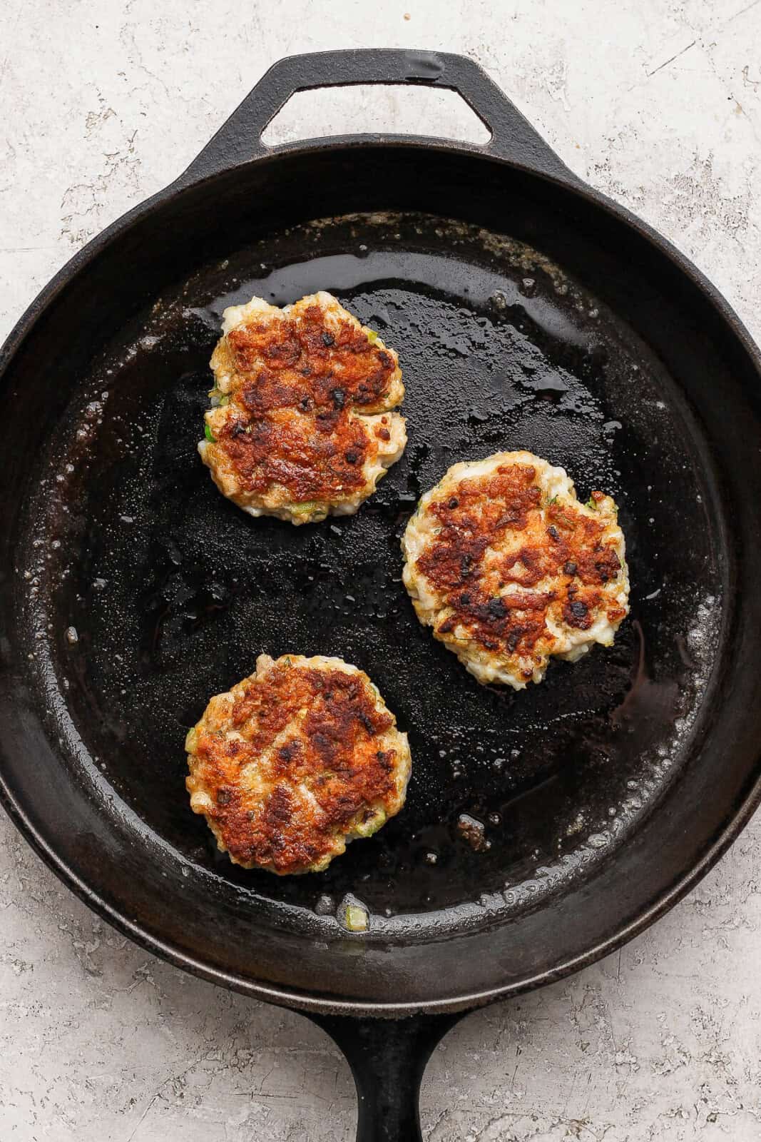 Cod fish cakes cooked and still in a cast iron skillet. 
