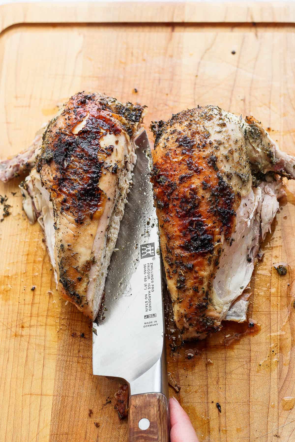The chicken breasts of a grilled spatchcock chicken being carved.