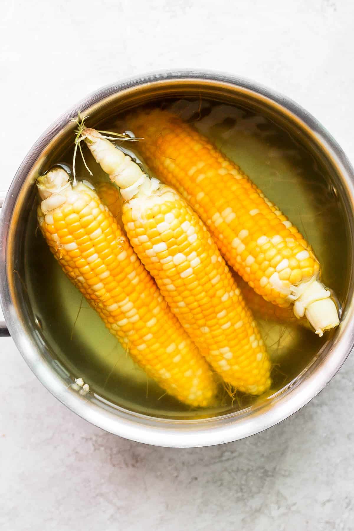 Boiled corn on the cob in a pot of water after cooking for a few minutes.