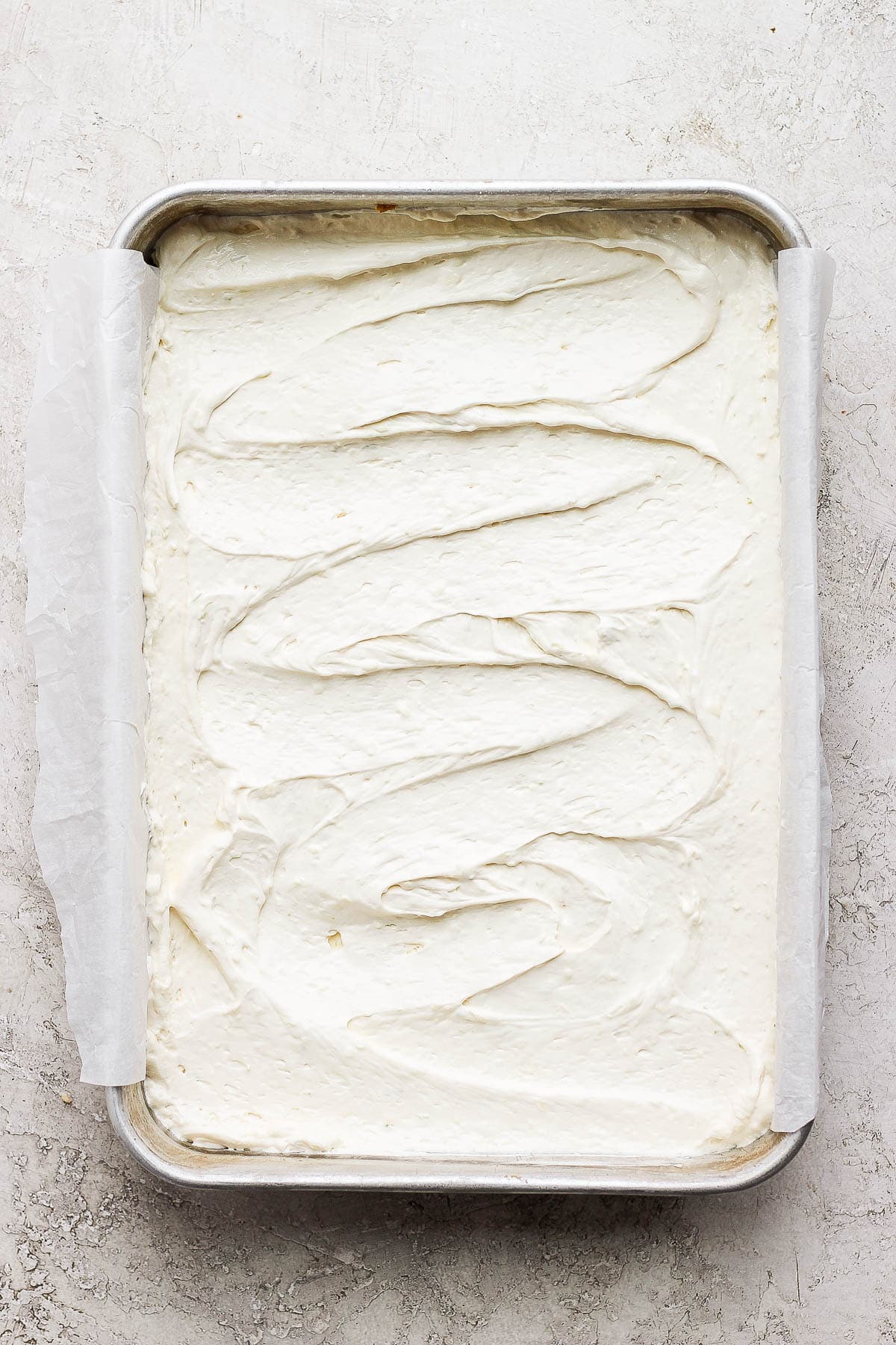 Key lime cheesecake bars in a metal baking pan before going in the fridge.