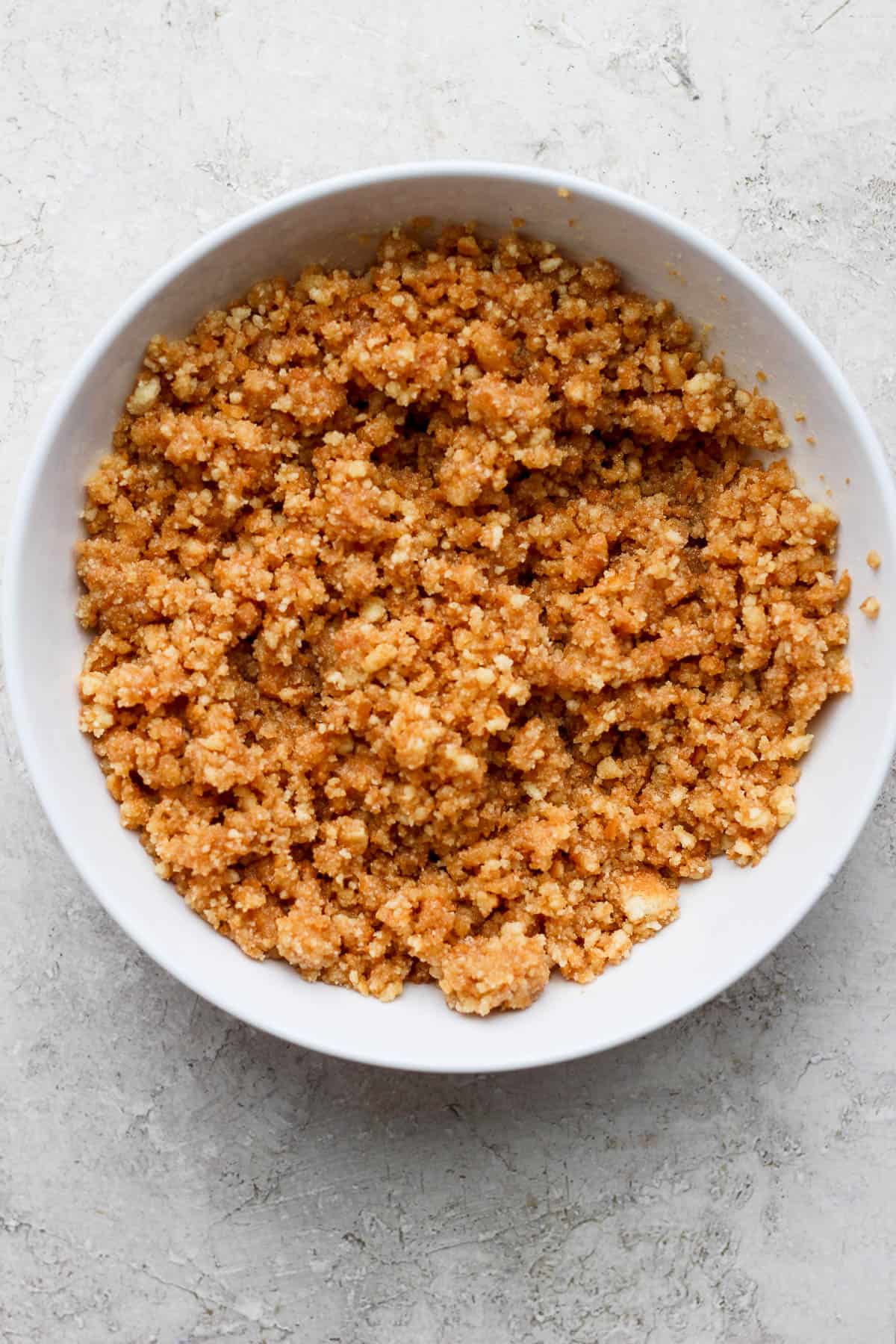 Melted butter and crushed Nilla Wafers mixed in a bowl to become the crust for key lime cheesecake bars.