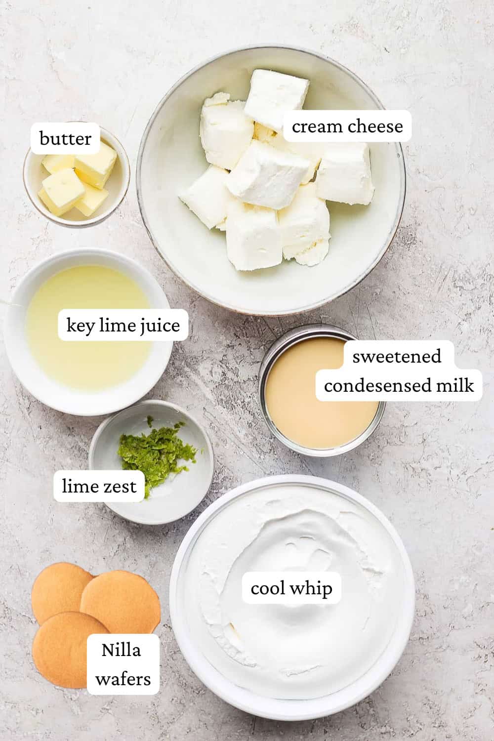 Ingredients for key lime cheesecake bars in separate bowls with labels.