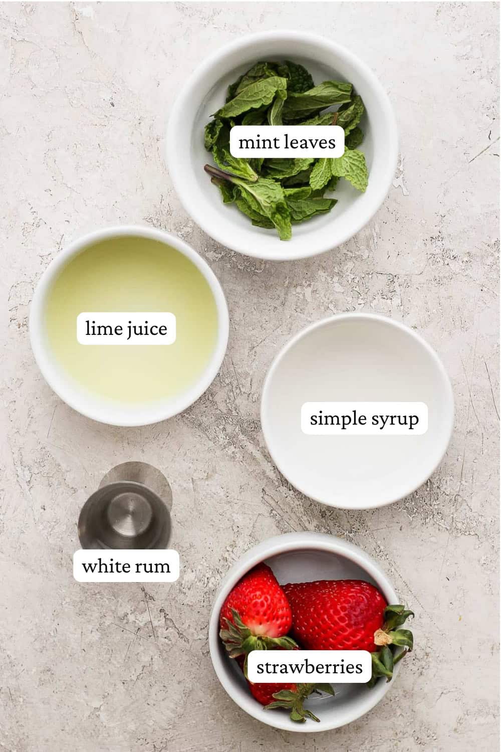 Ingredients for a strawberry mojito in separate bowls with labels.