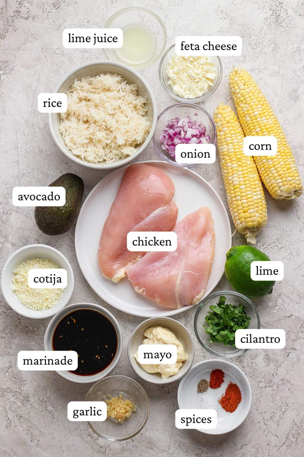 Ingredients for street corn chicken rice bowls separated into small bowls and plates and labeled.