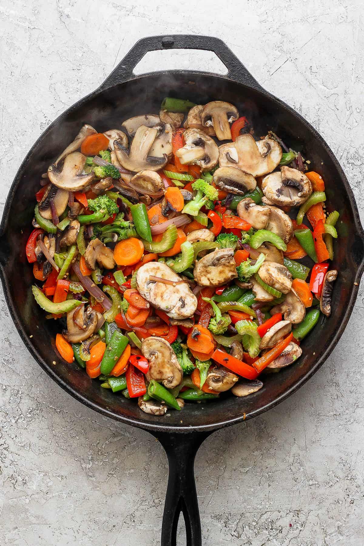 All the vegetables for veggie lo mein cooking in a cast iron skillet.