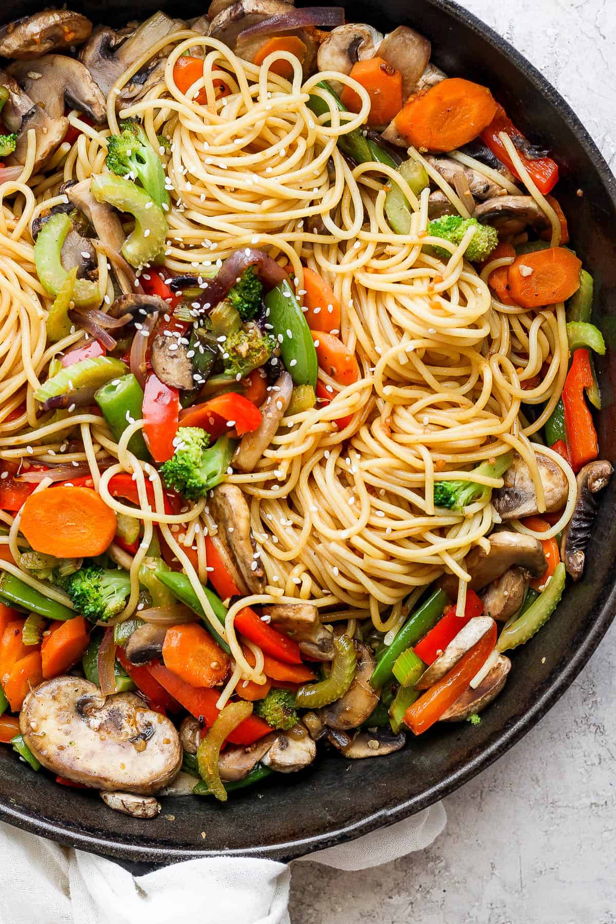 A fully cooked veggie lo mein in a cast iron skillet.