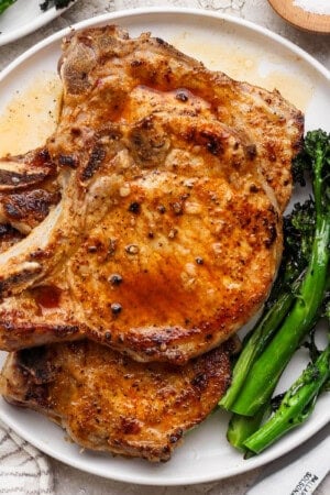 Blackstone pork chops on a plate with broccolini.