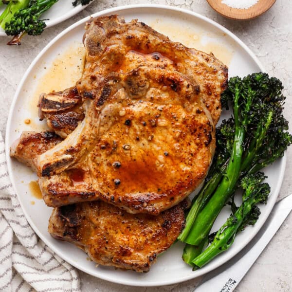 Blackstone pork chops on a plate with broccolini.