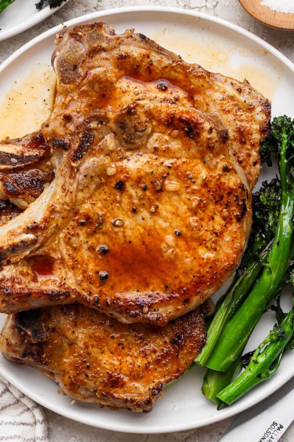 Blackstone pork chops on a plate with broccolini.