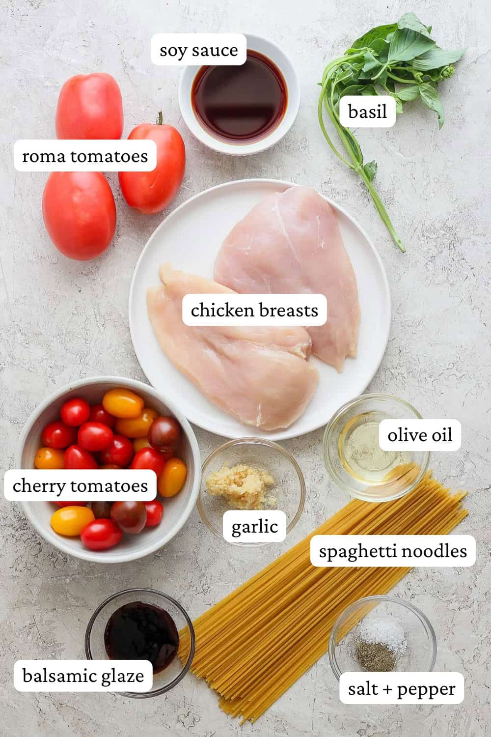 Ingredients for bruschetta chicken pasta on plates, in bowls, and on the counter with labels.