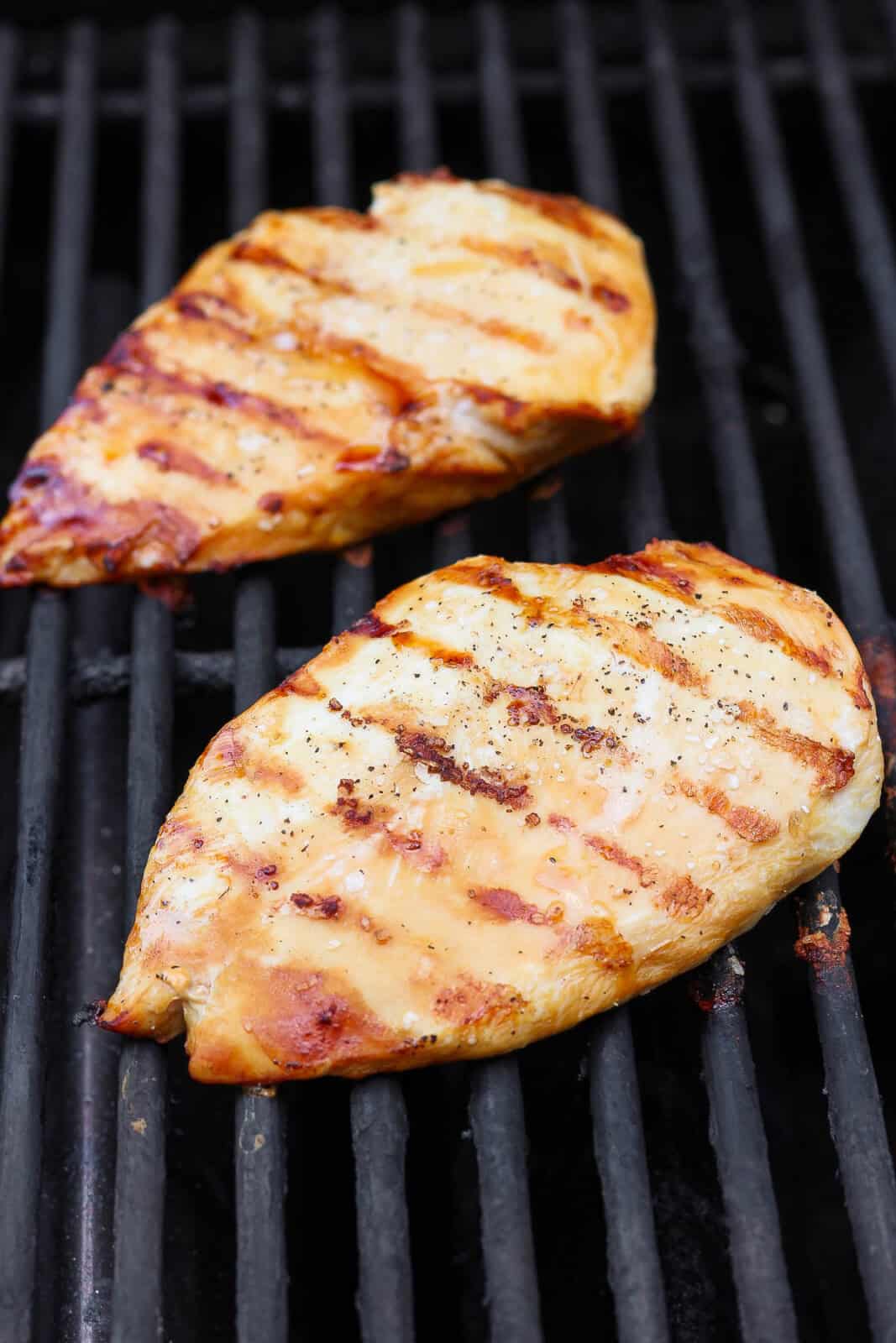 Two chicken breasts cooking on the grill to make bruschetta chicken pasta.