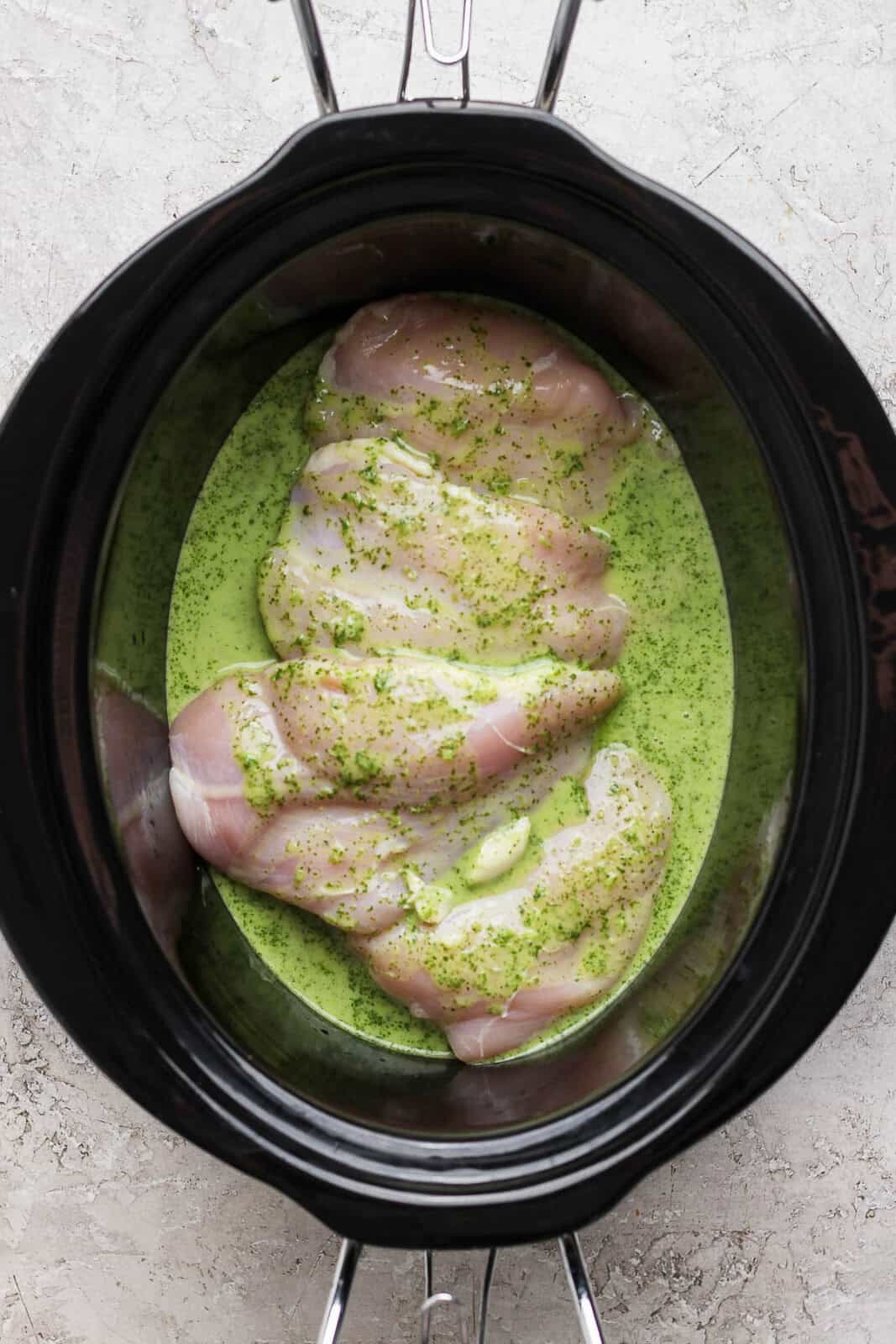 Cilantro lime sauce on raw chicken in a crockpot to make crockpot cilantro lime chicken.
