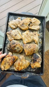 Grilled boneless and bone-in chicken thighs on a sheet pan after being cooked.