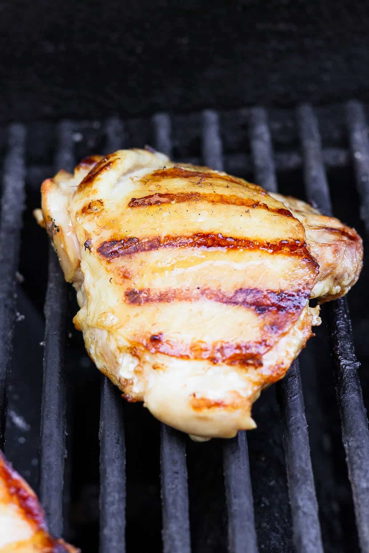 Grilled bone-in chicken thigh on a hot grill.