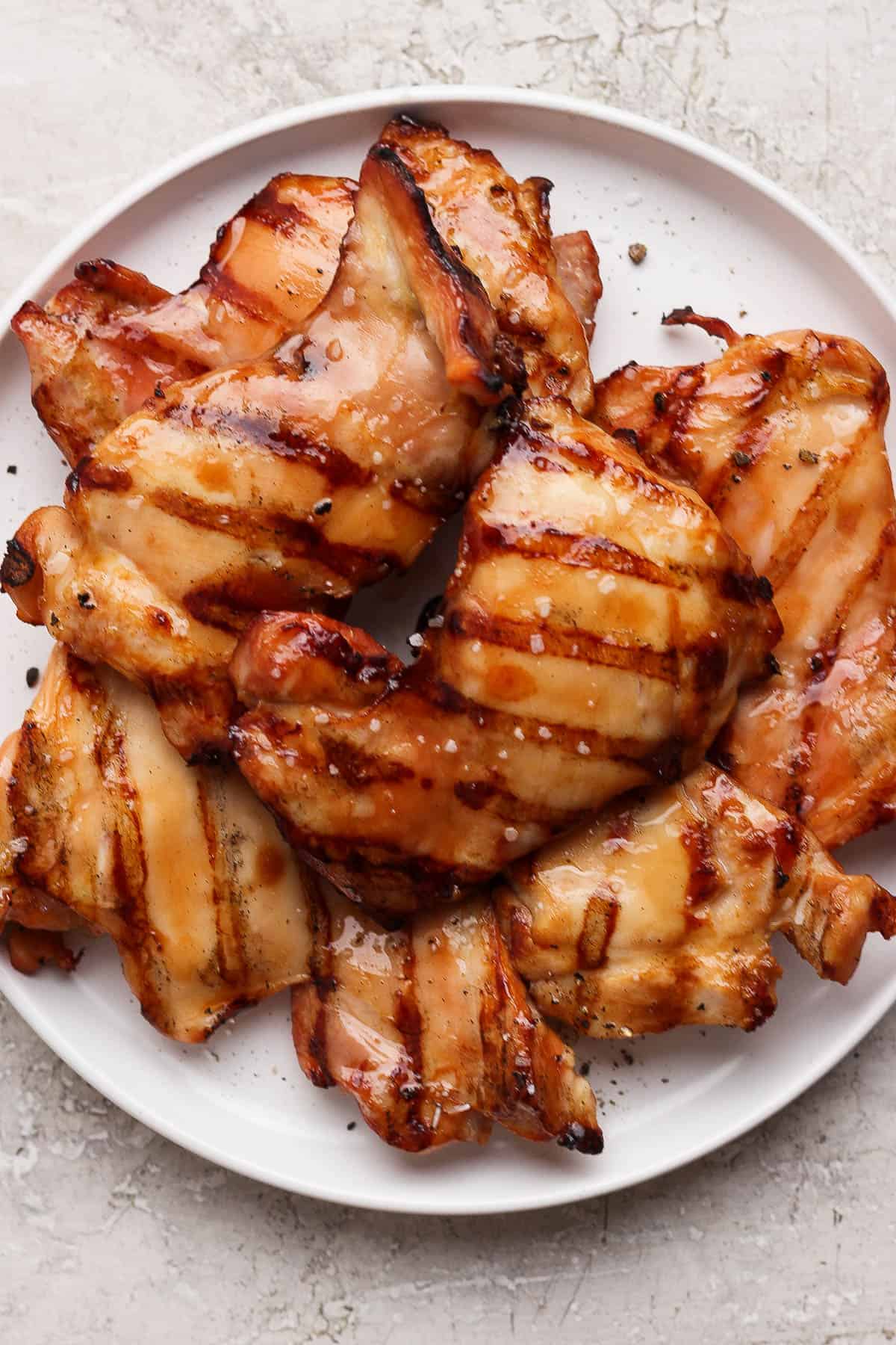 Grilled chicken thighs resting on a white plate.
