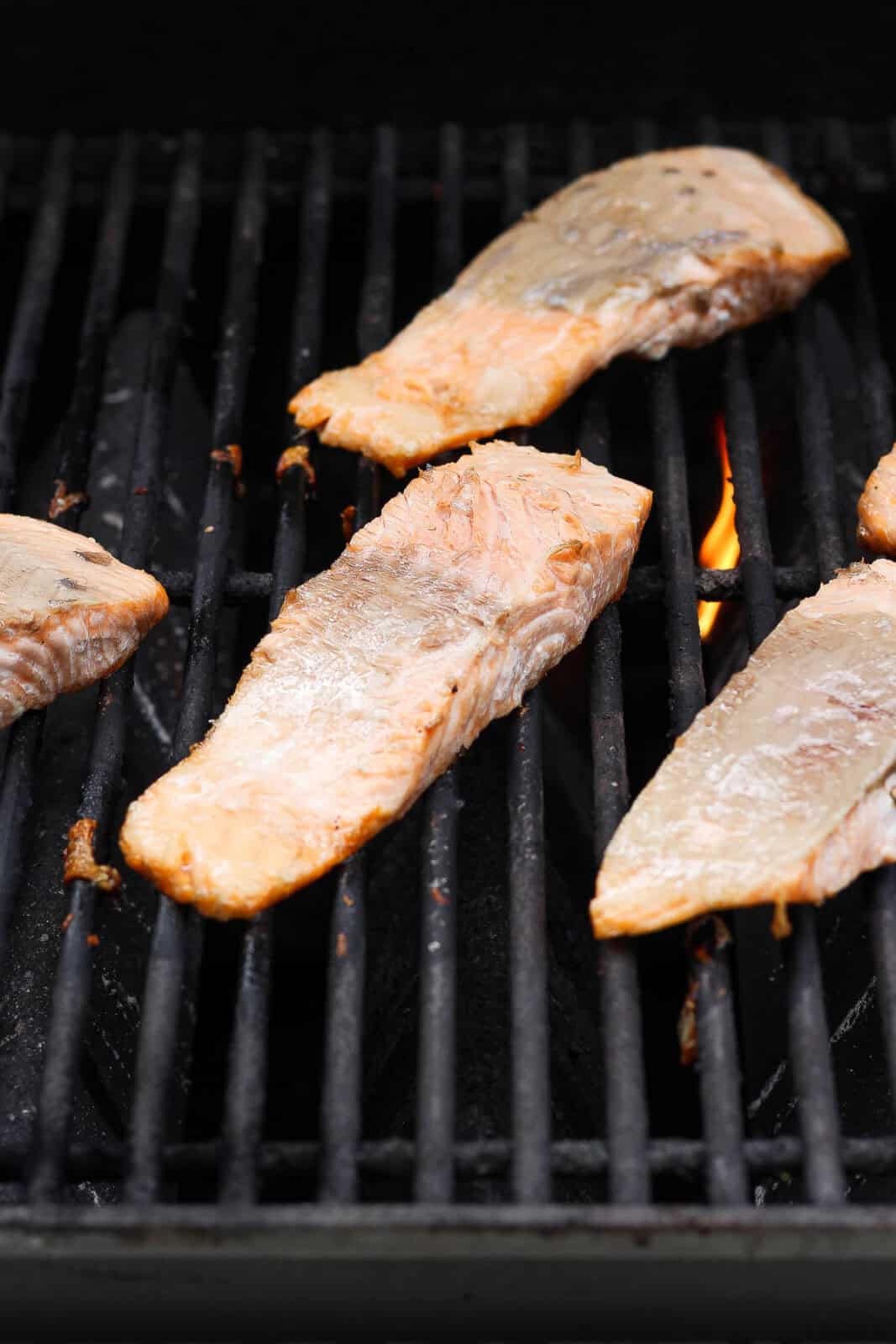 Grilled salmon fillets flipped over on the hot grill.
